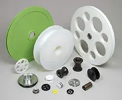 Group of UHMW sheaves and pulleys including weight-reduction designs and a green-rimmed sheave, with assorted bushings and small parts